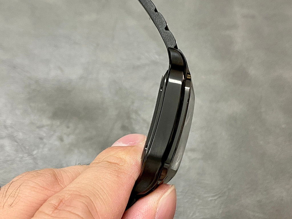Cartier watch side profile with black case and bracelet links on a black strap.