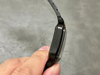 Cartier watch side profile with black case and bracelet links on a black strap.