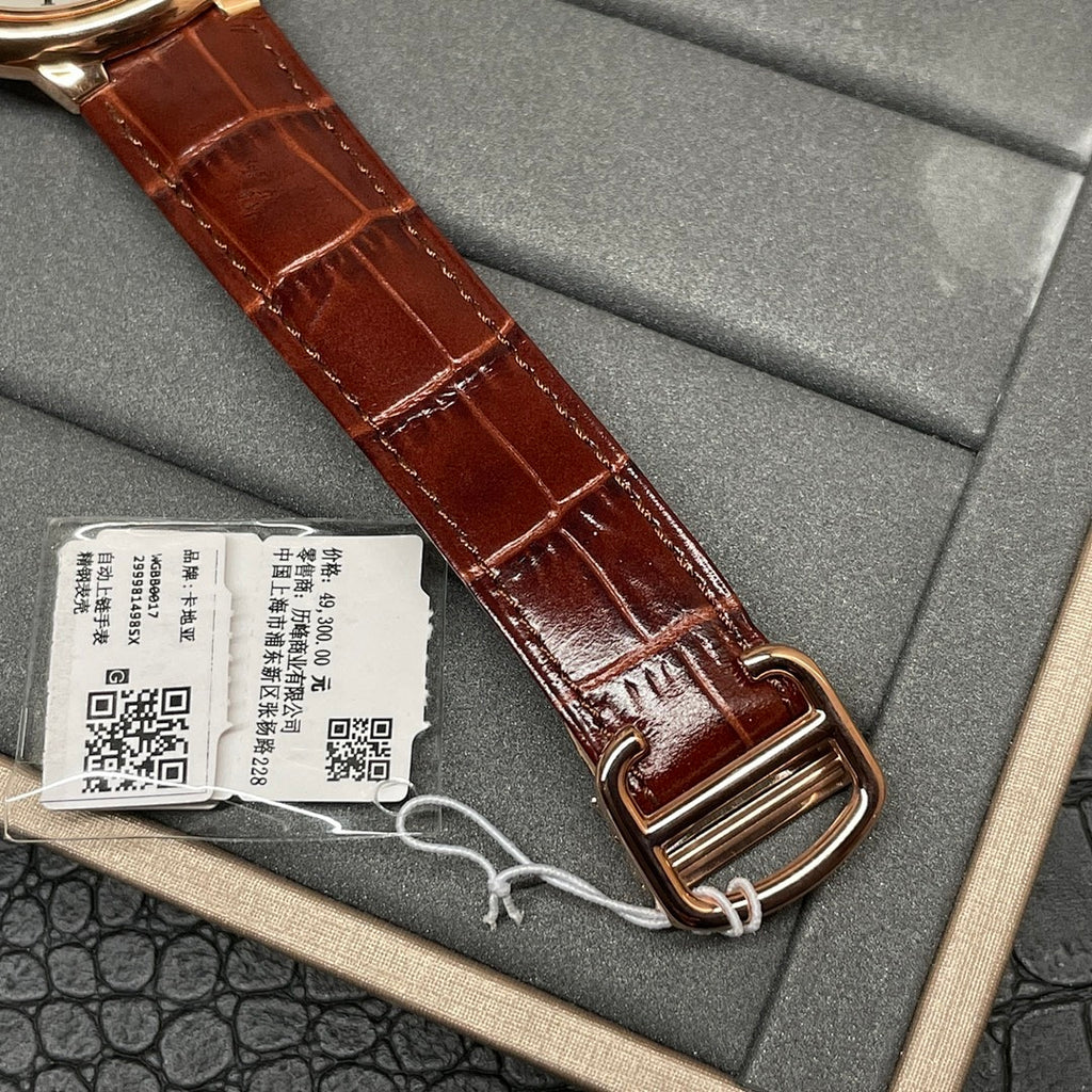 Cartier wristwatch close-up showing brown leather strap and rose-gold buckle in box