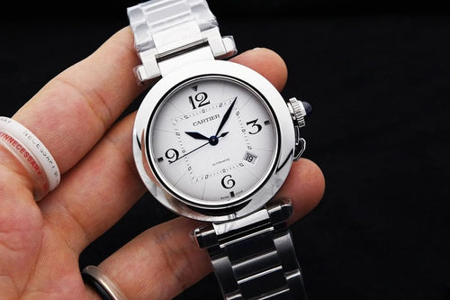 Cartier watch with white dial and black numerals, silver bracelet, held in hand
