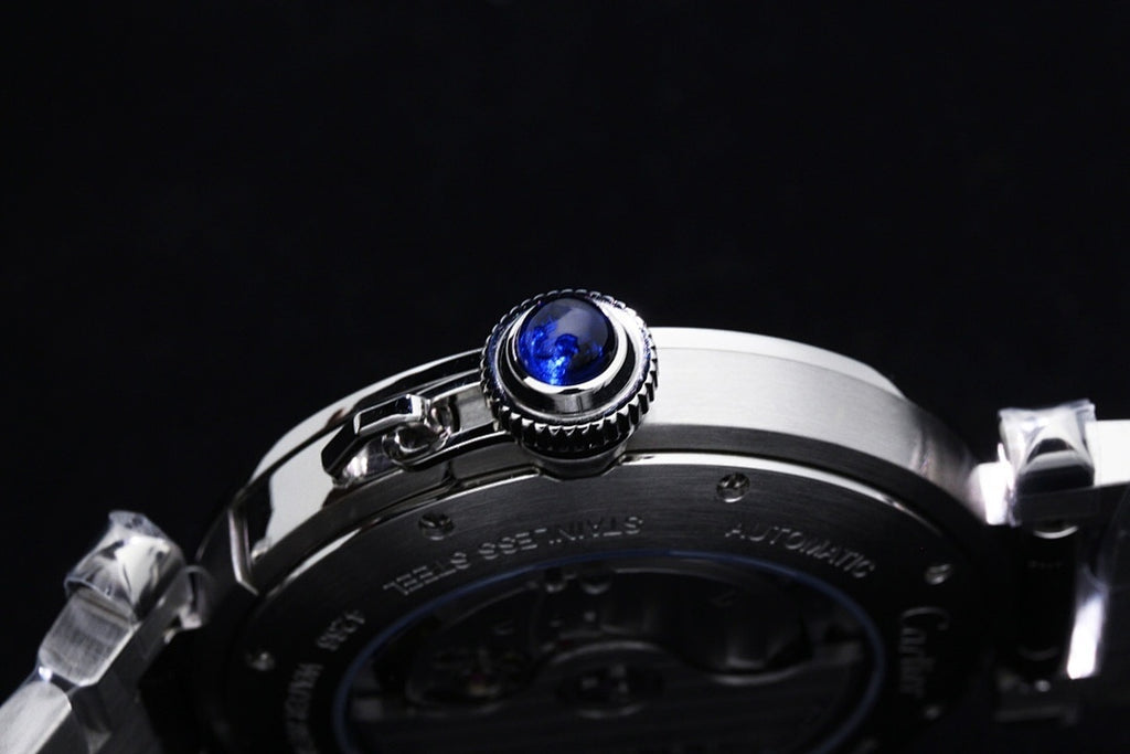 Cartier watch close-up of crown with blue gemstone on dark dial bezel