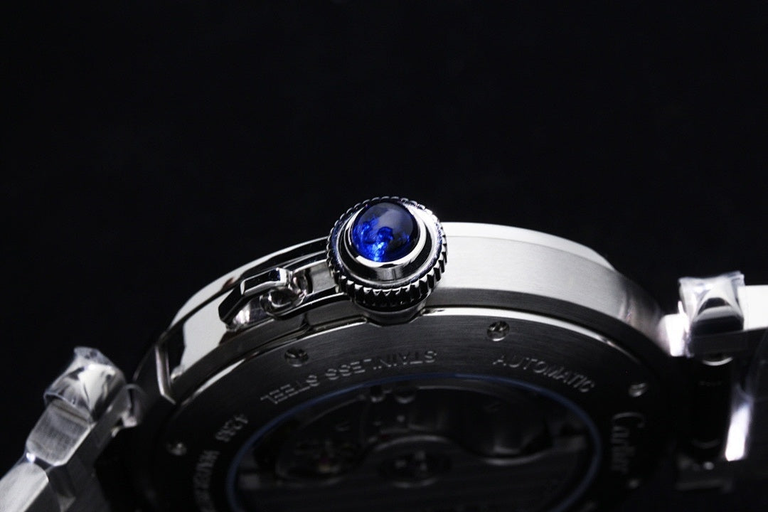 Cartier watch close-up of crown with blue gemstone on dark dial bezel