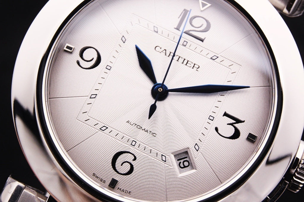 Cartier watch dial close-up with blue hands, Arabic numerals, and patterned face