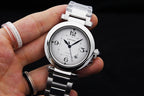 Cartier watch on wrist with white dial and silver link bracelet, held by hand