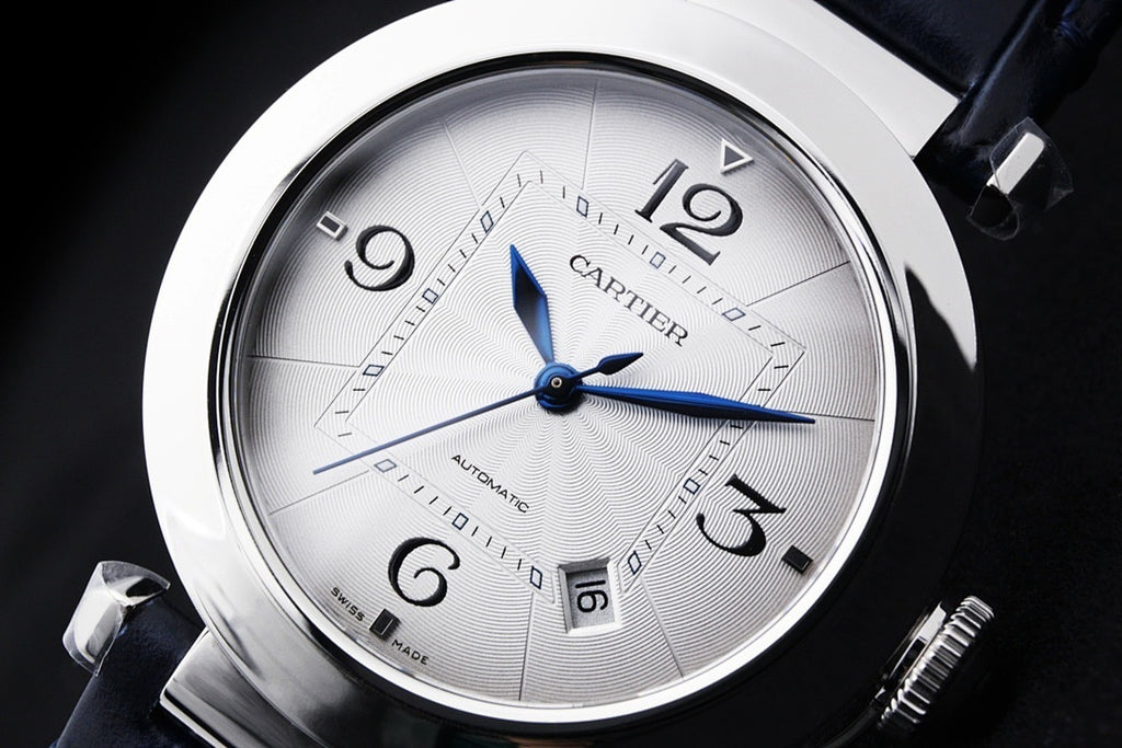 Cartier wristwatch face close-up with white dial, blue hands and date markers