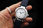 Cartier wristwatch on hand with dark blue leather strap and white dial