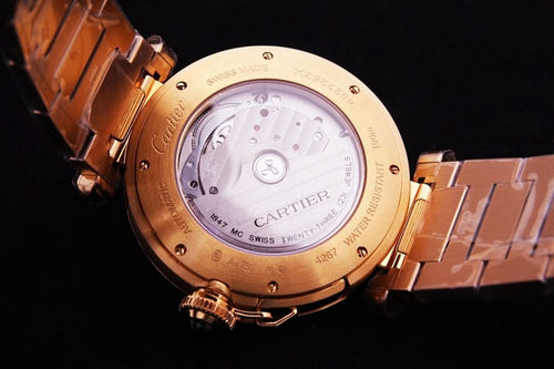 Cartier watch caseback with engraved gold cover and visible movement through glass