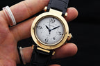 Cartier watch on hand with white dial, gold-tone case, and black leather strap