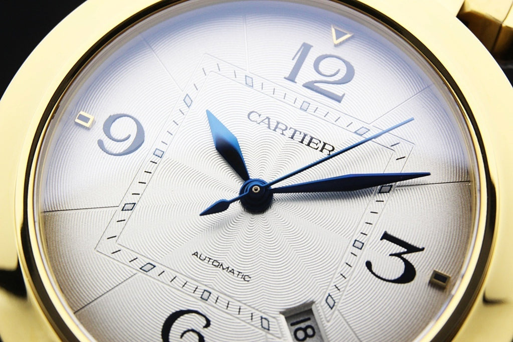 Close-up of Cartier white dial with blue hour/minute hands and Arabic numerals.