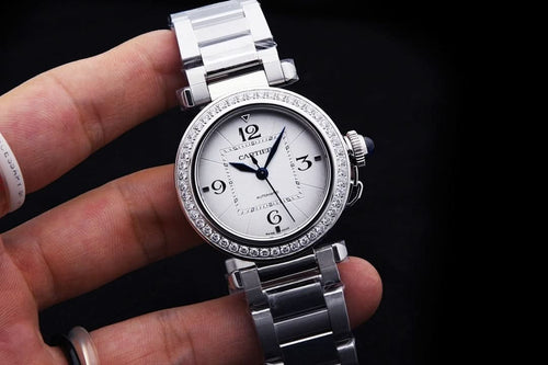 Cartier wristwatch with silver steel bracelet, diamond bezel, white dial and black hands.