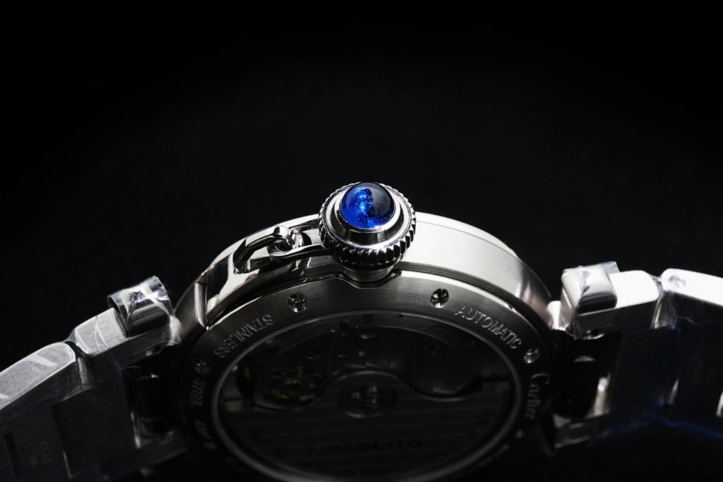 Cartier watch caseback with prominent blue screw and stainless steel band links.