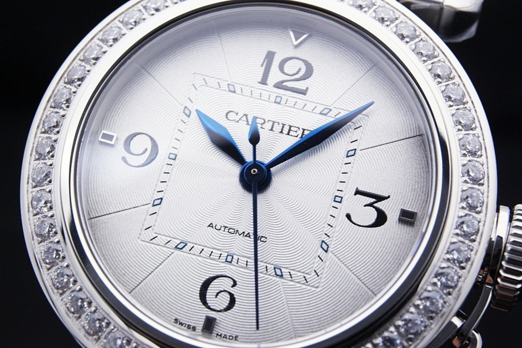 Cartier automatic wristwatch face with white dial, blue hands, diamond bezel.