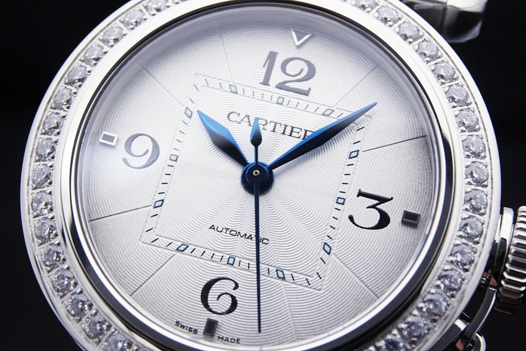 Cartier automatic wristwatch face with white dial, blue hands, diamond bezel.