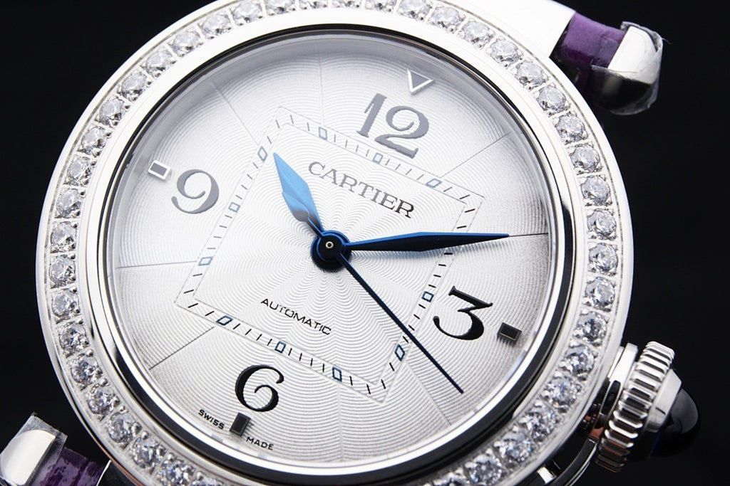 Cartier watch dial with blue hands, jeweled silver bezel, automatic on white face