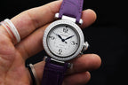 Cartier watch on purple leather strap, silver jeweled bezel, white dial close-up