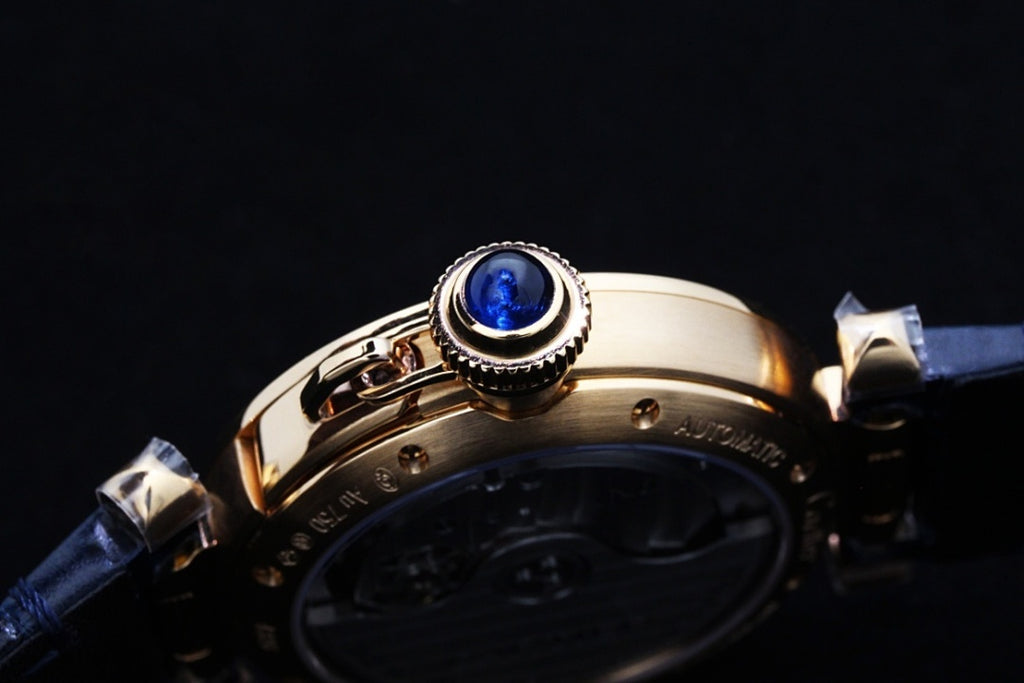 Cartier watch crown area with blue gem detail and gold case, blue leather strap