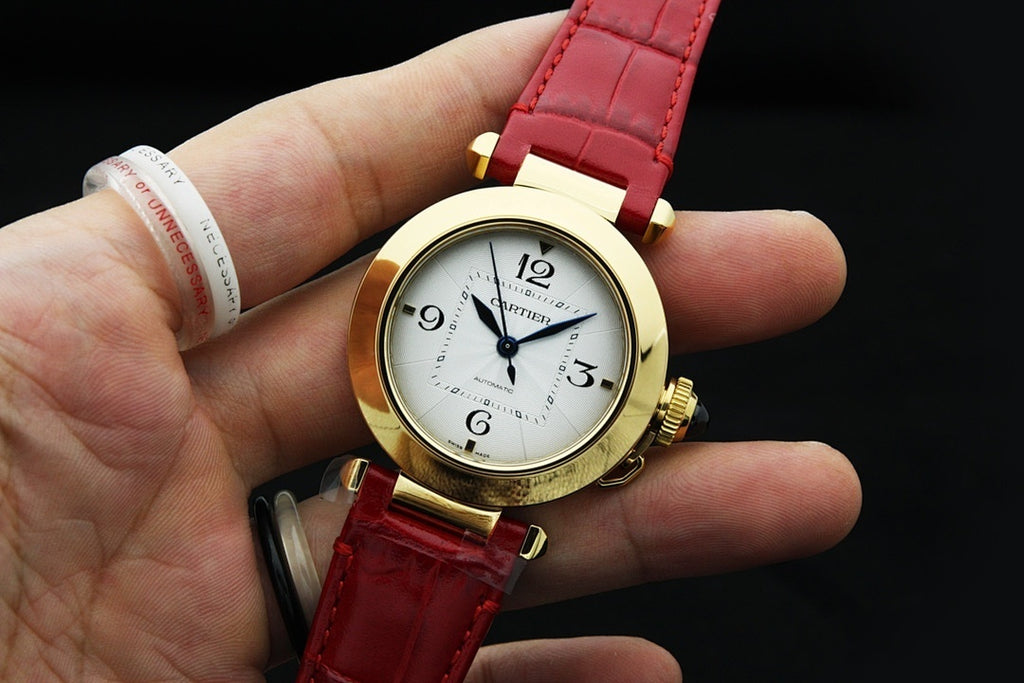 Cartier watch on hand with gold-tone case, white dial and red leather strap
