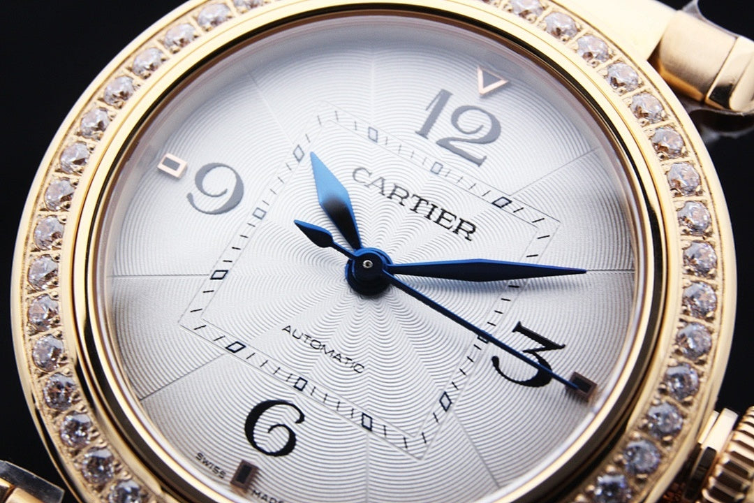 Gold wristwatch with white dial, blue hands, Roman numerals, and diamond bezel