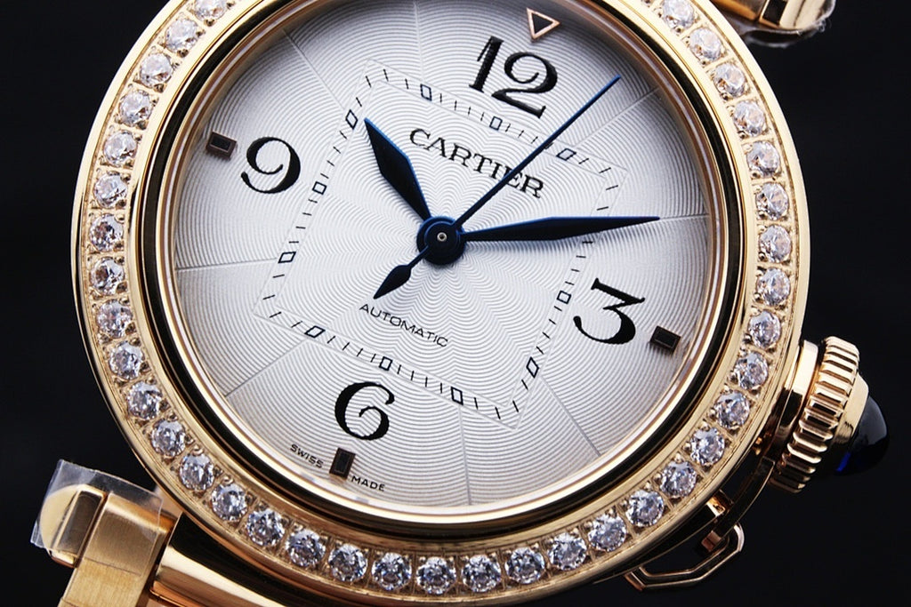 Gold wristwatch with white dial, blue hands, Roman numerals, and diamond bezel