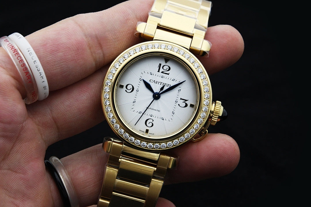 Gold-tone Cartier wristwatch on hand with jeweled bezel and white dial