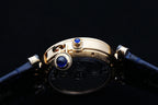 Cartier watch case detail with blue jewel accents and gold-tone hardware, blue strap