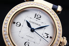 Cartier watch close-up with white dial, blue hands, diamond-studded gold bezel