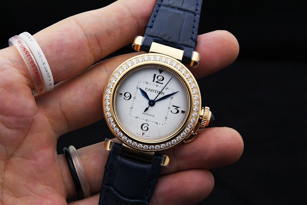 Gold-tone Cartier wristwatch with white dial and diamond bezel, blue leather band held up