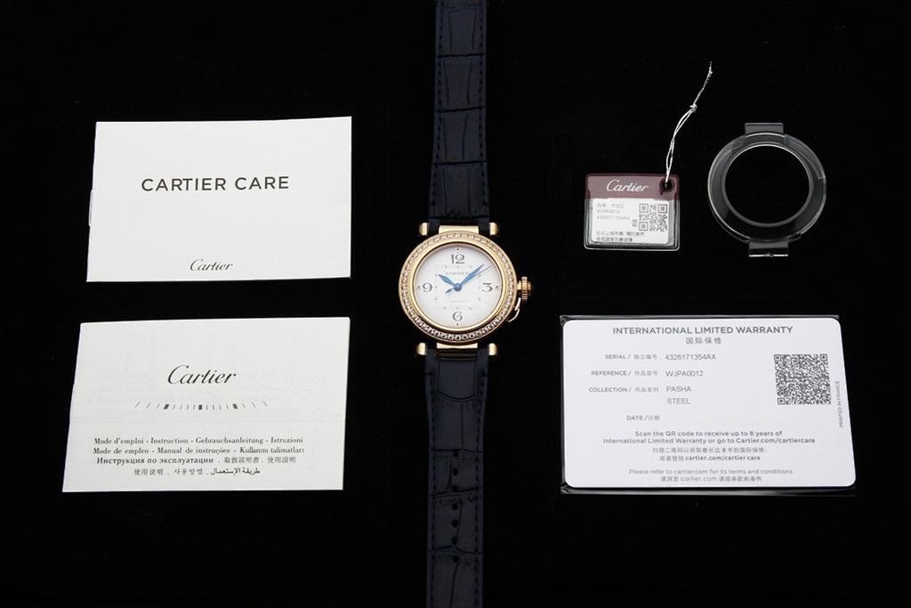 Cartier watch on blue leather strap with care and warranty papers and small accessory items