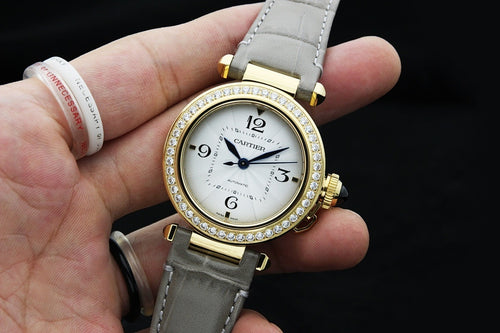 Cartier watch with white dial, gold bezel with crystals, and gray leather strap