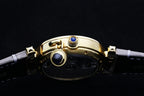 Cartier watch with gold case and blue crown accents on gray leather strap