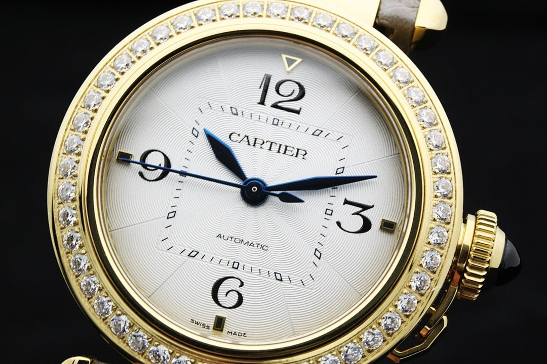 Cartier watch close-up with white dial, gold bezel with crystals, and blue hands