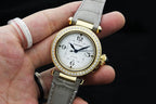 Cartier watch with white dial, gold bezel with crystals, and gray leather strap
