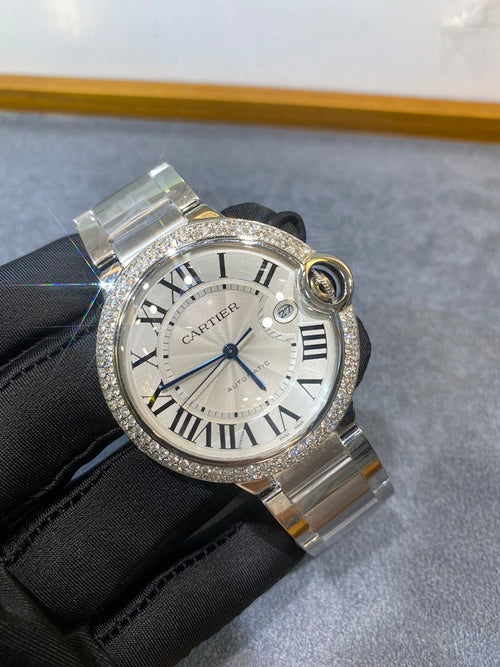 Silver diamond-bezel wristwatch with white Roman dial and metal link bracelet, crown detail