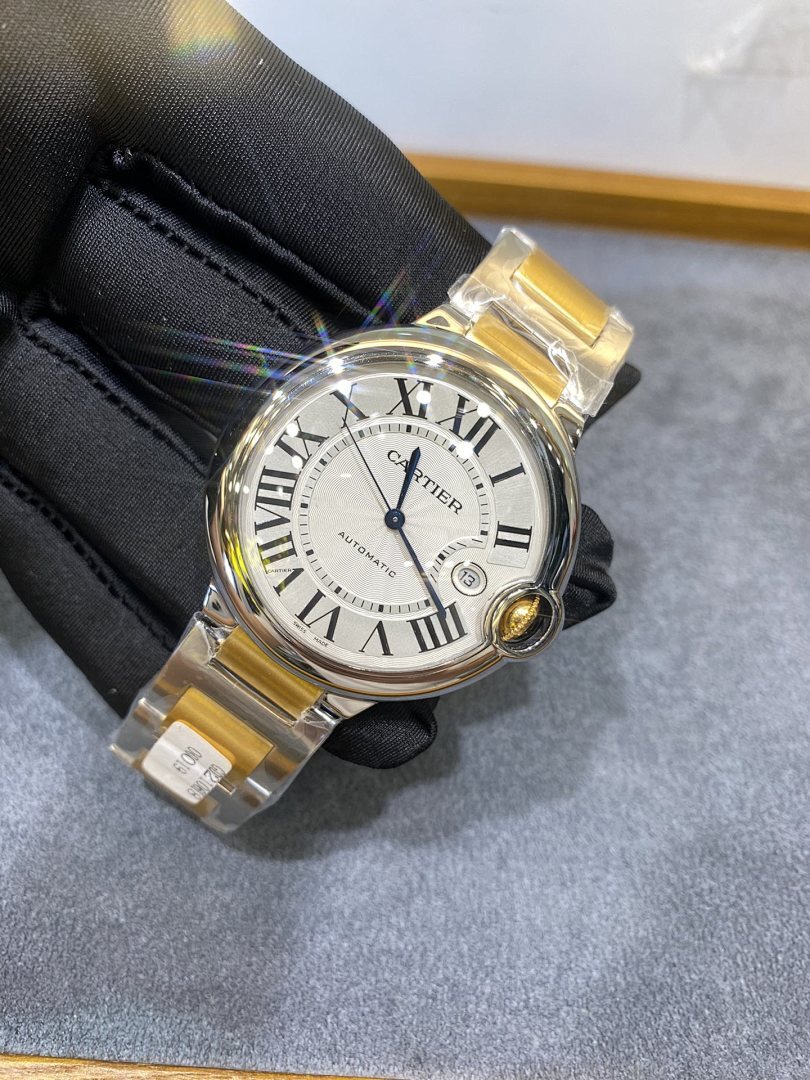 Cartier watch with black glove holding white dial, gold bezel, silver two-tone bracelet