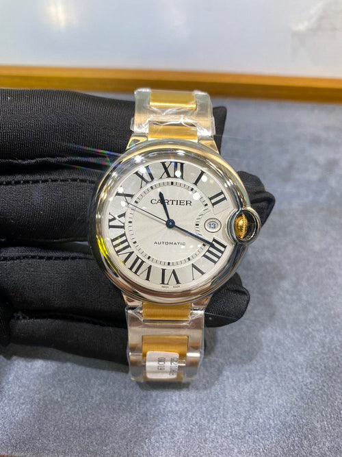 Cartier watch with white dial, Roman numerals, gold bezel, and silver two-tone bracelet