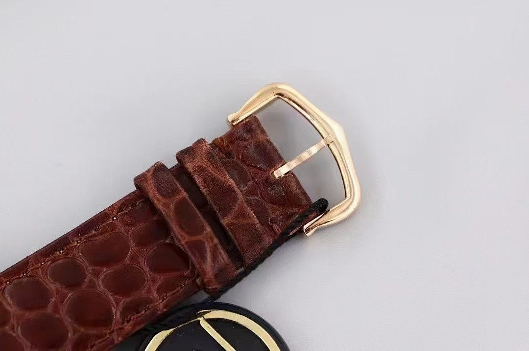 Rectangular watch case with gold-tone frame and dark brown crocodile-style leather strap