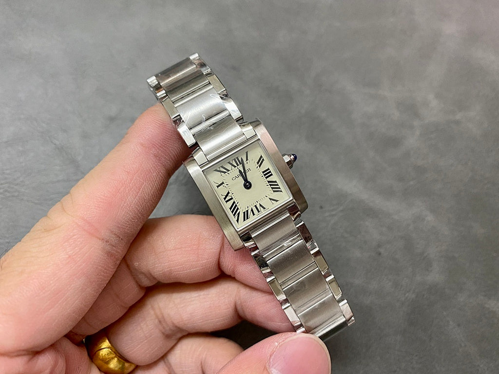 Cartier rectangular wristwatch with cream dial, Roman numerals, silver bracelet in hand.