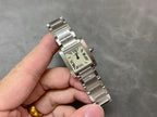 Cartier rectangular wristwatch with cream dial, Roman numerals, silver bracelet in hand.
