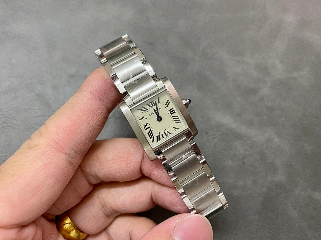 Cartier rectangular wristwatch with cream dial, Roman numerals, silver bracelet in hand.