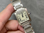 Cartier rectangular watch face close-up with Roman numeral dial, silver bracelet, blue crown.