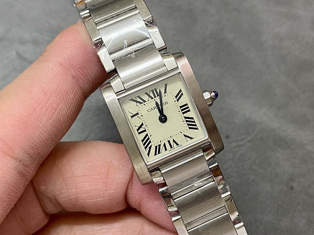 Cartier rectangular watch face close-up with Roman numeral dial, silver bracelet, blue crown.