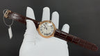 Cartier watch on brown leather strap with Roman numeral dial, circular gold case