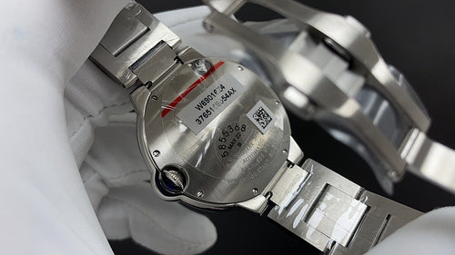 Cartier watch case back with stainless steel bracelet links and engraved serial plate.