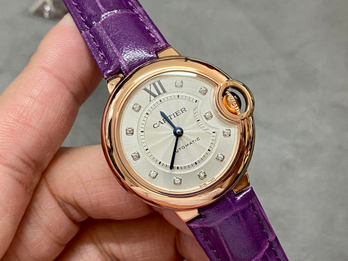 Cartier oval watch from the side, purple leather strap and gold-tone crown button.
