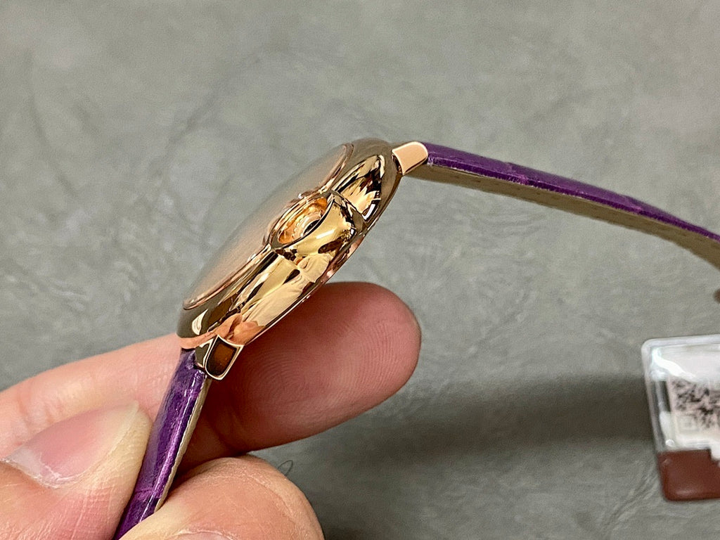 Cartier watch case and side profile with purple leather strap, gold-tone finish.
