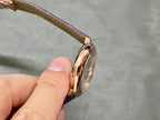 Cartier watch side profile with purple leather strap, gold-tone case edge and crown.