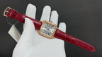 Cartier watch with red leather strap and gold-toned case on white gloves