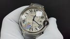 Wristwatch with white Roman numeral dial, blue hands, iridescent element at lower bezel