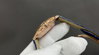 Cartier wristwatch open case with blue strap and gold-toned interior on gloves