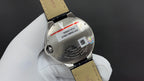 Cartier watch caseback with markings and iridescent logo, leather strap and clasp visible.